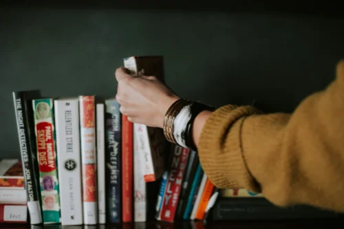 Woman grabbing a book from a shelf