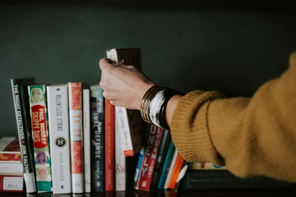 Woman grabbing a book from a shelf